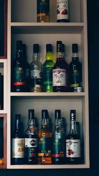 Vertical shot of various liquor bottles neatly arranged on a shelf indoors.