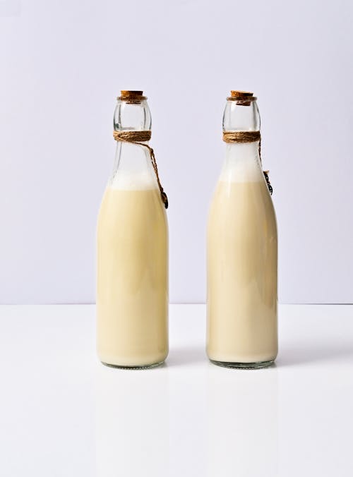 A Glass Bottles with Milk on a White Surface