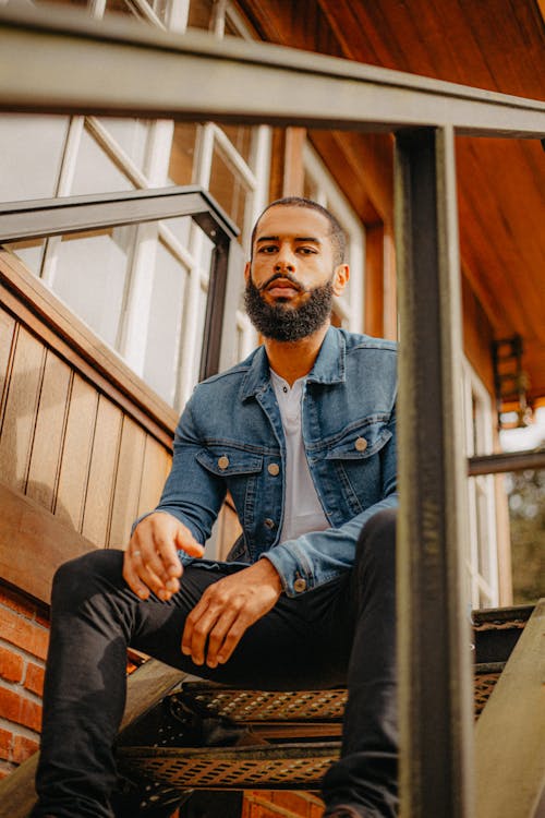 Free Man in Jean Jacket with Beard Sitting on Staircase Stock Photo