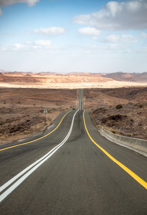 Free A long, empty highway stretching into a desert landscape under a bright blue sky. Stock Photo