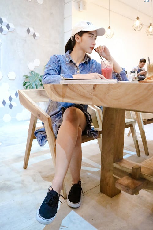 無料 部屋の中の茶色のテーブルの近くの茶色の木製の椅子に座っている女性 写真素材