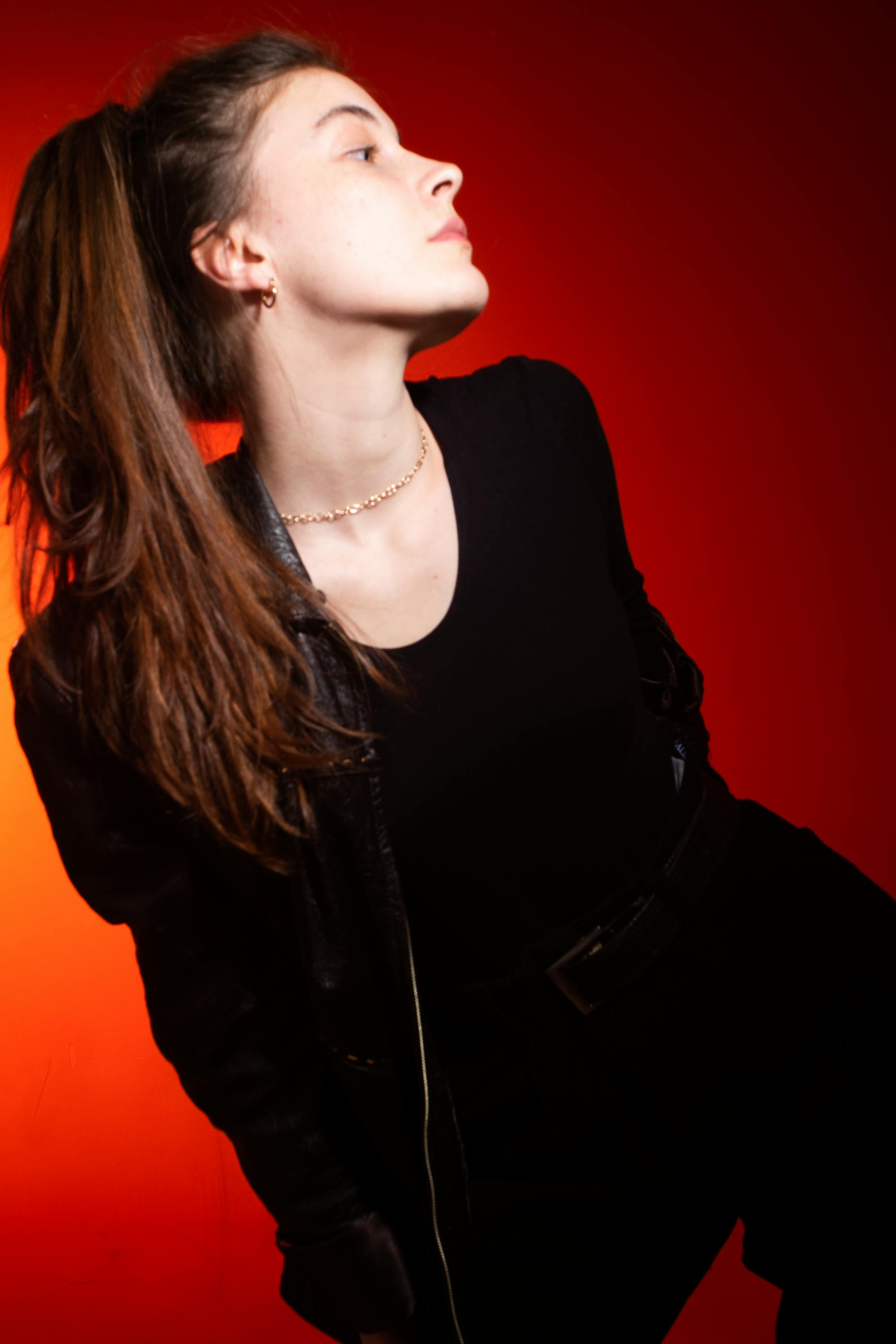 Free Stylish woman in black posing against vibrant red background. Fashion photoshoot. Stock Photo