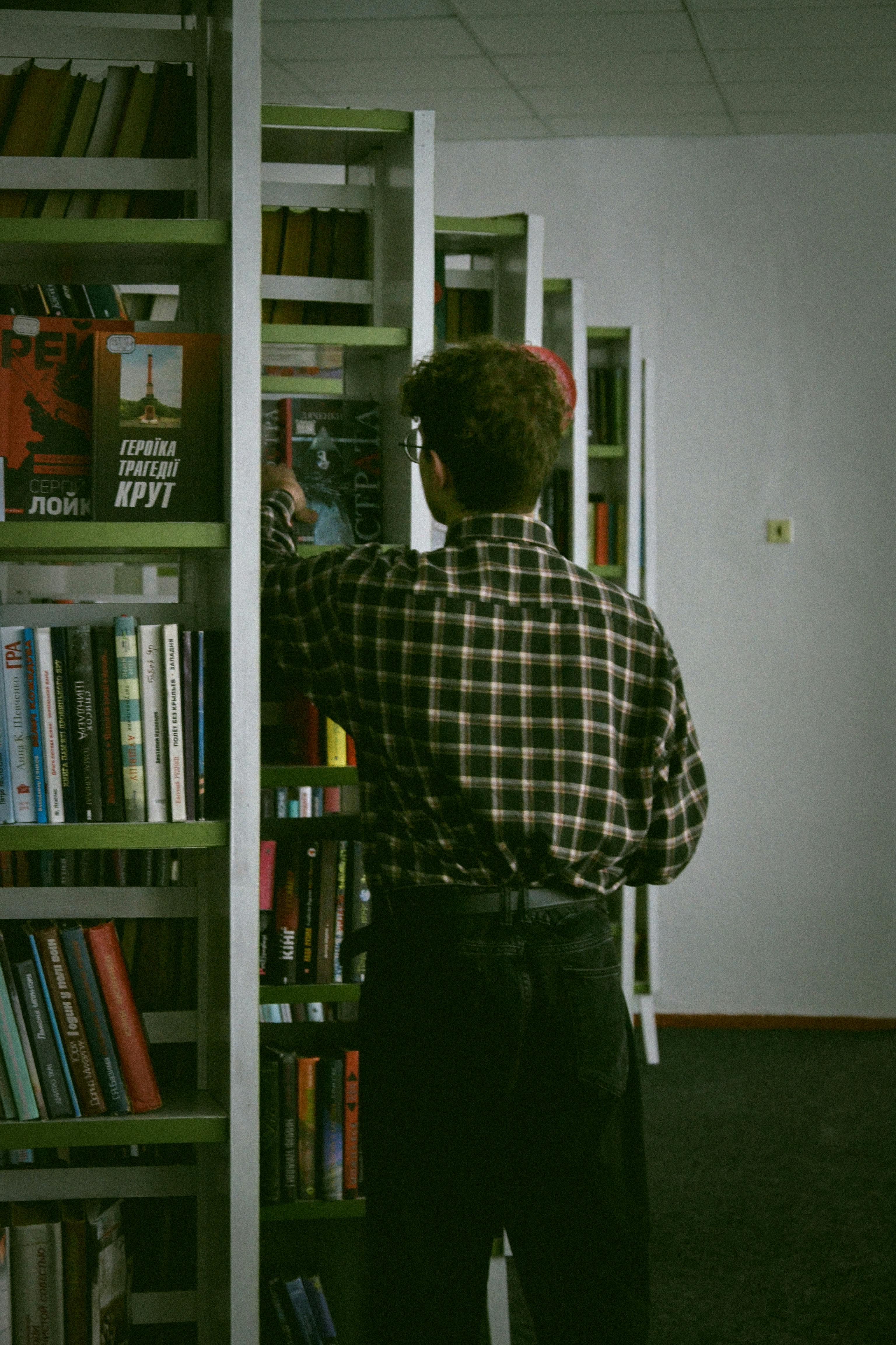 A Man Fixing Bookshelves in the Library · Free Stock Photo