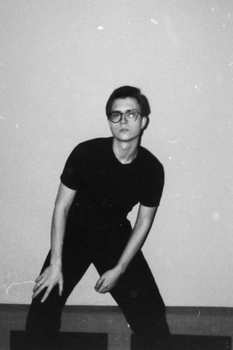 Artistic black and white portrait of a young man in glasses, posing confidently indoor.