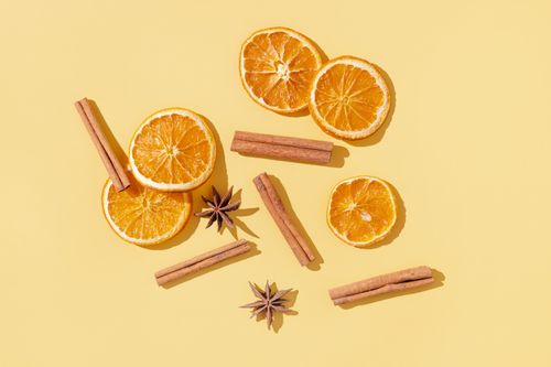 Free Overhead view of cinnamon sticks and dried orange slices on yellow background. Stock Photo