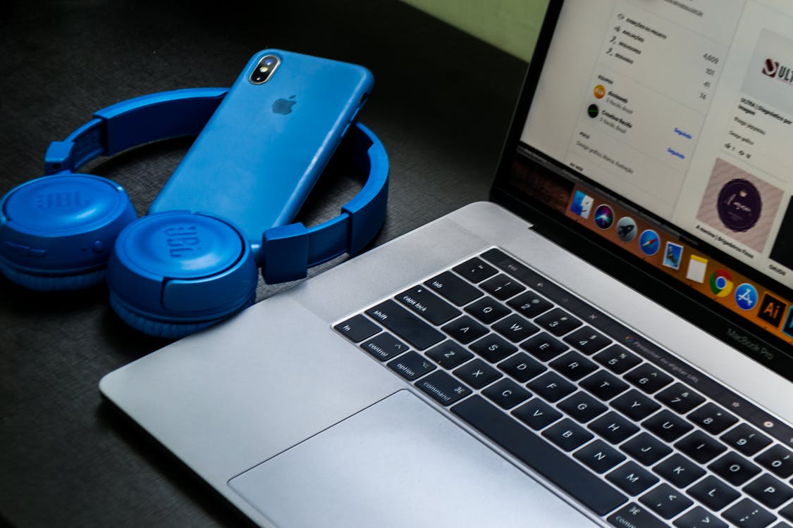 Macbook Pro Obok Niebieskich Słuchawek Bezprzewodowych