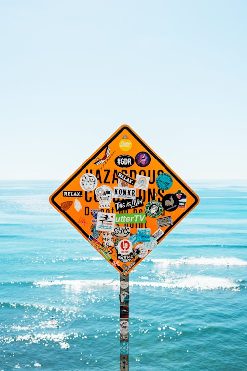 Stickers Covering a Warning Sign Standing Against the Sea