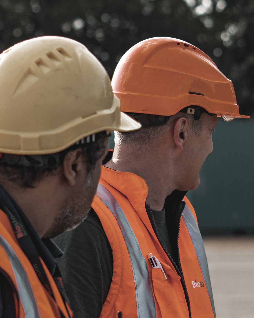 Two workers in hard hats and safety vests on site