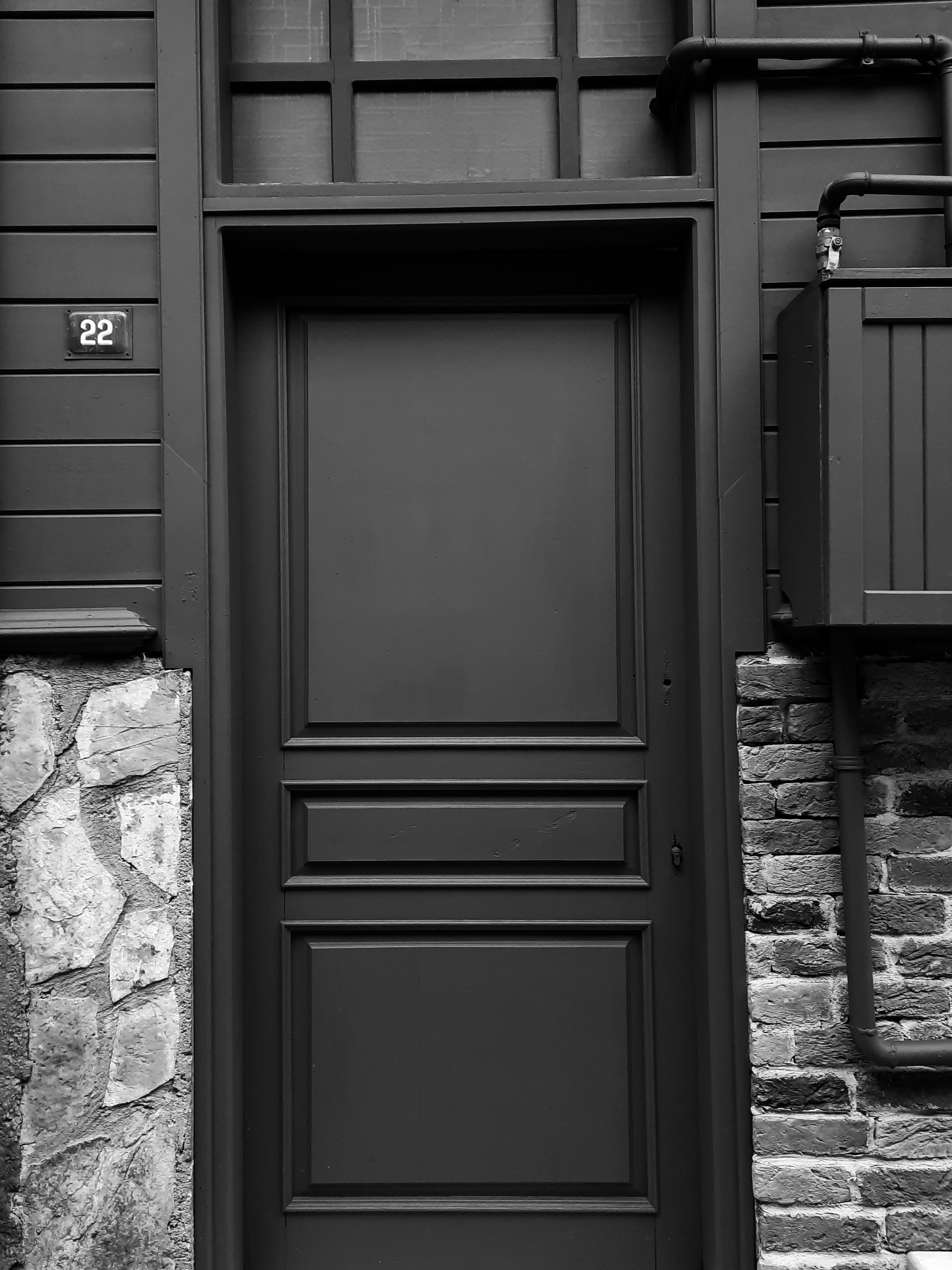 Elegant black door with number 22 against a stone and brick facade, showcasing classic architecture.
