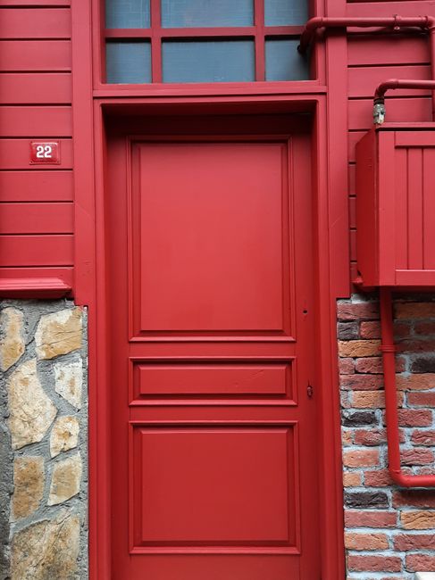 A vibrant red door surrounded by brick and stone accents, creating a rustic, charming facade.