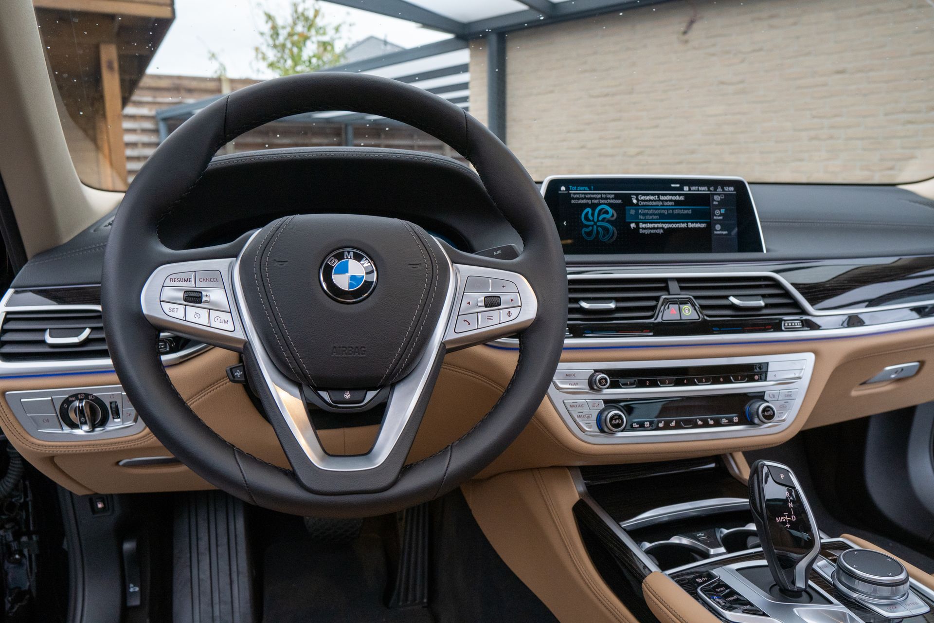 Elegant car interior featuring a leather steering wheel, dashboard, and high-tech controls.
