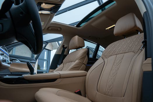 Elegant car interior featuring beige leather seats and a panoramic sunroof, highlighting luxury and comfort.