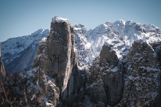 Majestic snow-covered rocky peaks under a clear blue sky in winter.