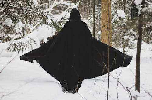 Back View of a Person in Black Clothes Walking on Snow