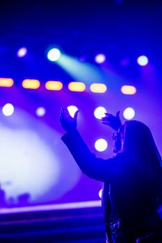 A woman enjoying a lively concert with colorful stage lights and an excited crowd.