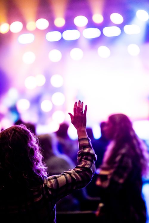 Free Colorful concert scene with vibrant lights and crowd enjoying the music with hands raised. Stock Photo
