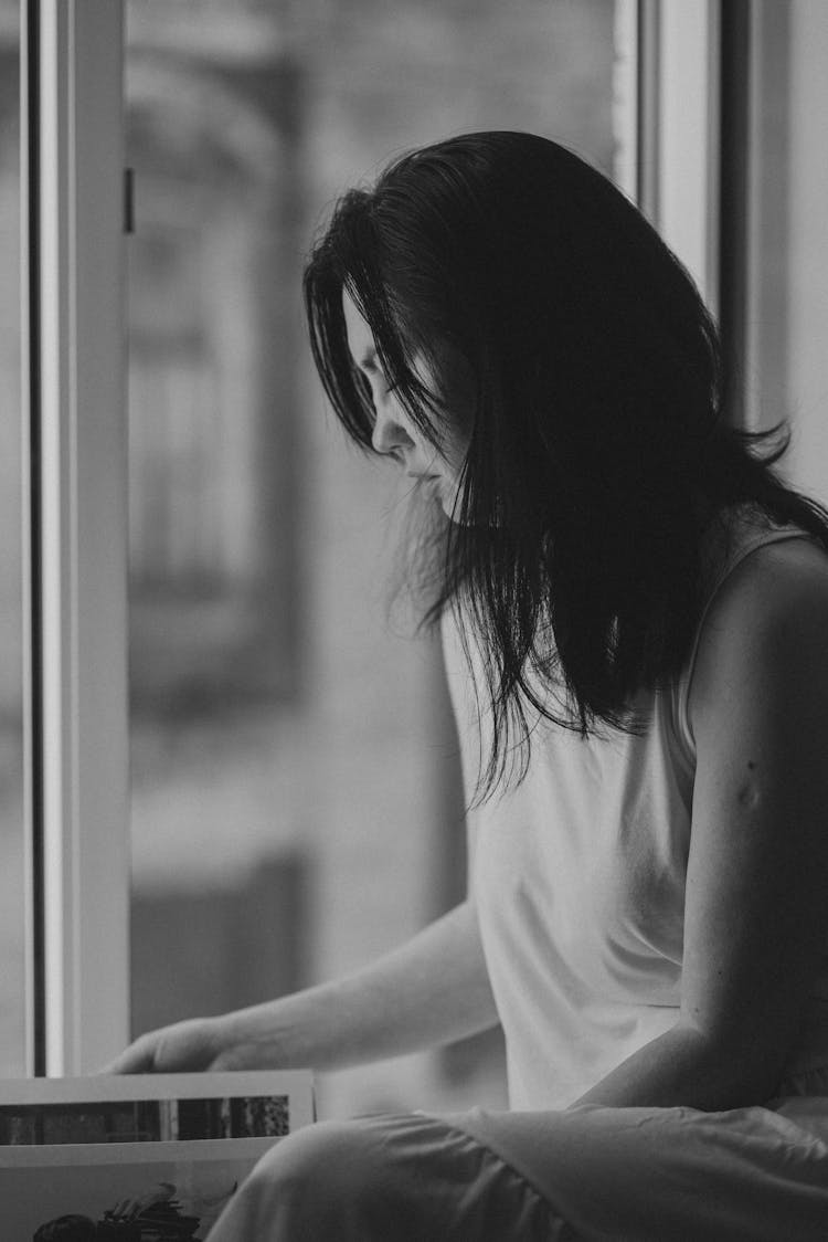 Black And White Photo Of Woman Sitting By Window