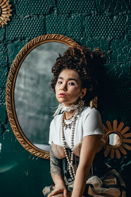 Free Charming woman with vintage curls poses by an ornate mirror, exuding classic elegance. Stock Photo
