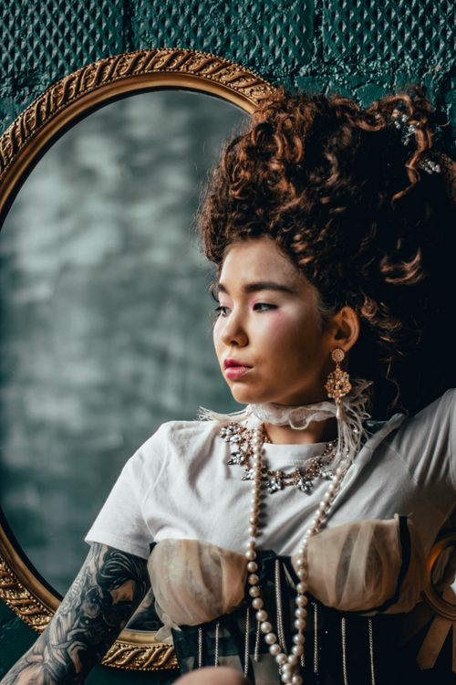 Free A stylish portrait of a woman with vintage fashion and elaborate hairstyle, reflected in a mirror. Stock Photo