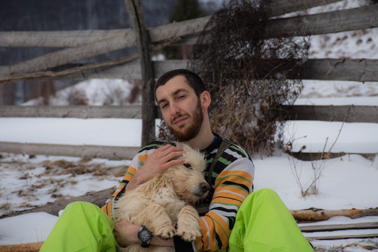 Man Hugging A Dog While In The Snow