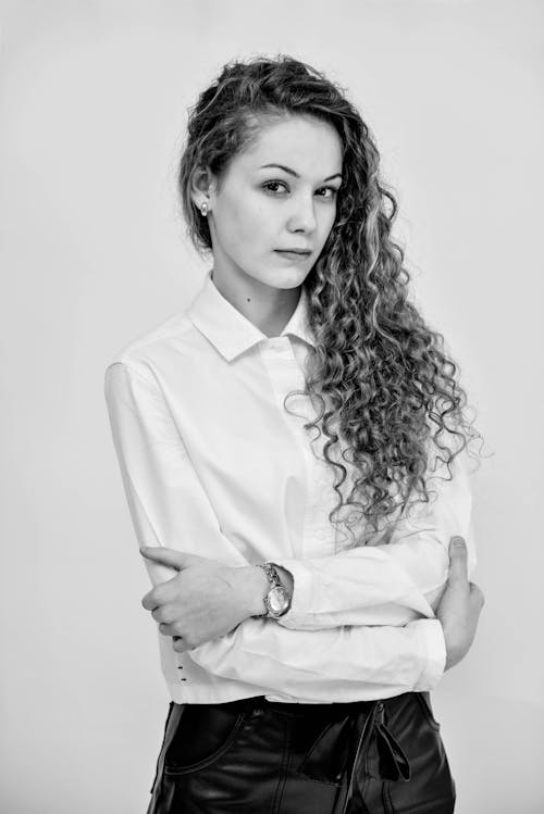 A Grayscale Photo of a Woman in White Long Sleeves with Her Arms Crossed