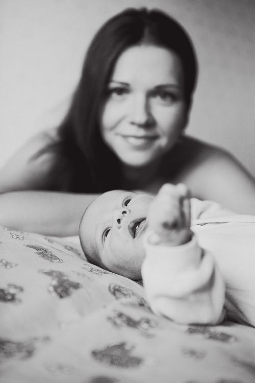 A Grayscale Photo of a Baby Lying Down Near Her Mother