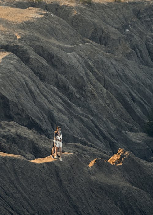 An Aerial Photography of a Couple Standing Together on a Rock Formation
