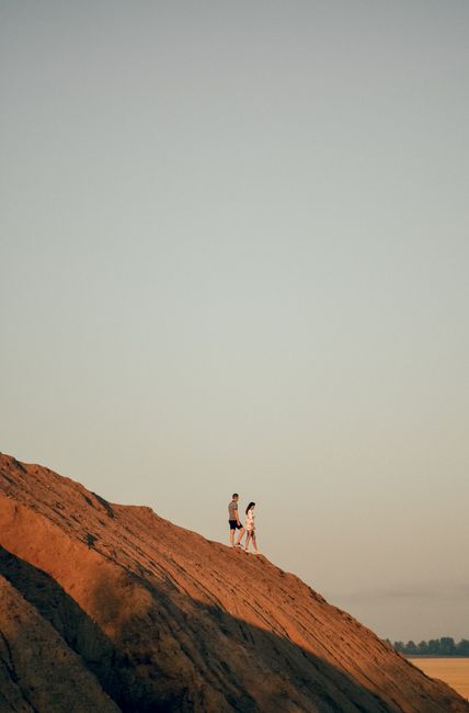 A couple walks on a rocky hill under a clear sky during daytime, ideal for outdoor themes.
