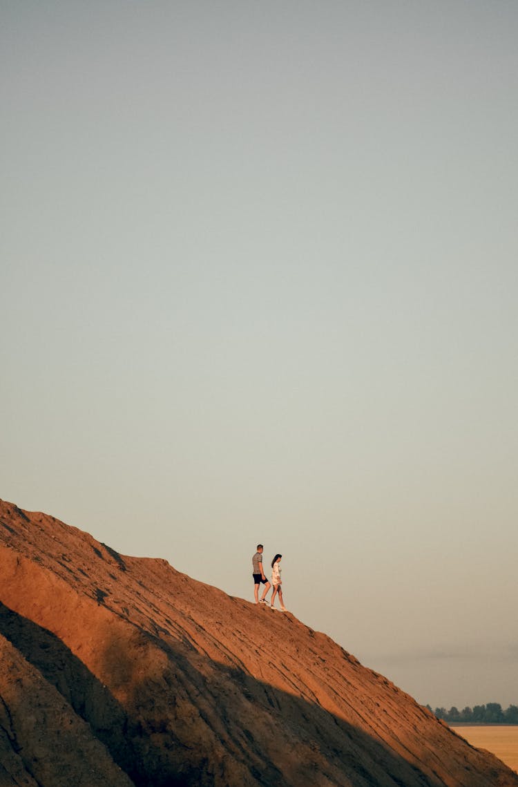 Man And Woman Walking Down Rocky Hill