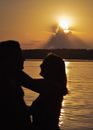 Silhouette of Man and Woman Standing Near Body of Water during Sunset
