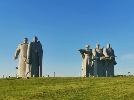 Panfilov Heroes Memorial sculptures standing majestically in a green field under a clear blue sky.