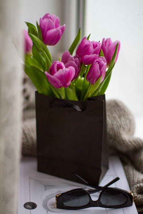 Free A Tulips in Full Bloom with Green Leaves on a Black Paper Bag Stock Photo