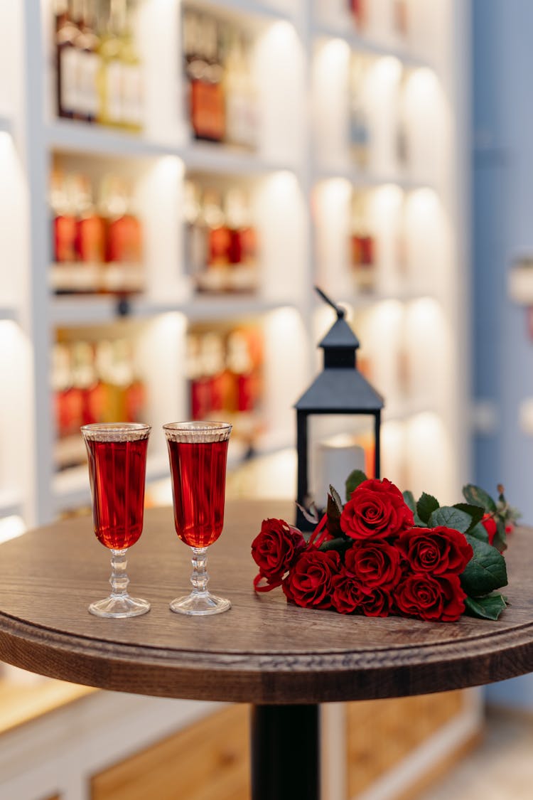 Two Red Wines Lantern And Bunch Of Roses On Wooden Table