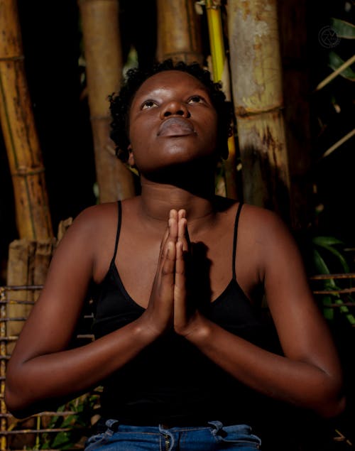 A Woman in Black Spaghetti Strap Top Looking Up with Her Hands Together