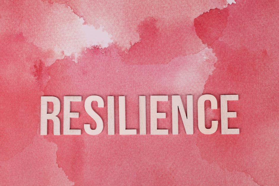 Word 'Resilience' on a pink watercolor background, symbolizing strength.