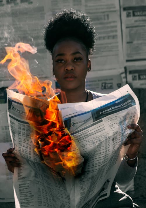 Free A Woman Holding a Burning Newspaper Stock Photo