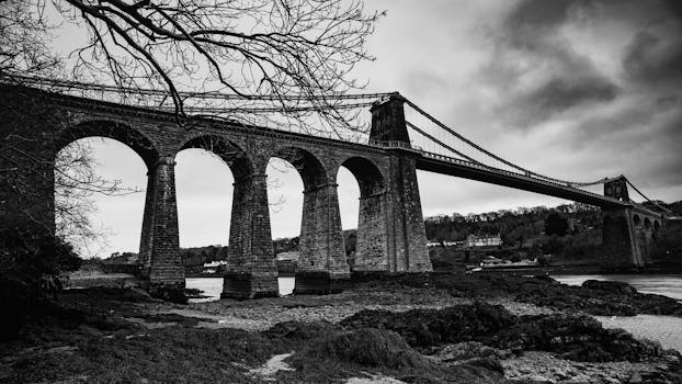 Dramatic black and white photo of the iconic Menai Bridge in Wales.