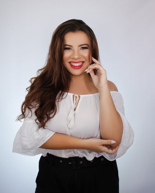 Free Portrait of a cheerful woman posing in a studio, wearing a white blouse and smiling broadly. Stock Photo