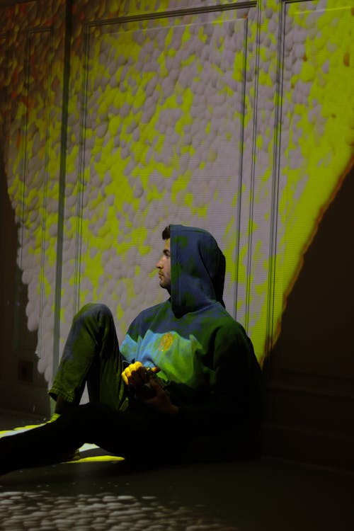 A Man Wearing Hoodie Jacket Sitting on the Floor