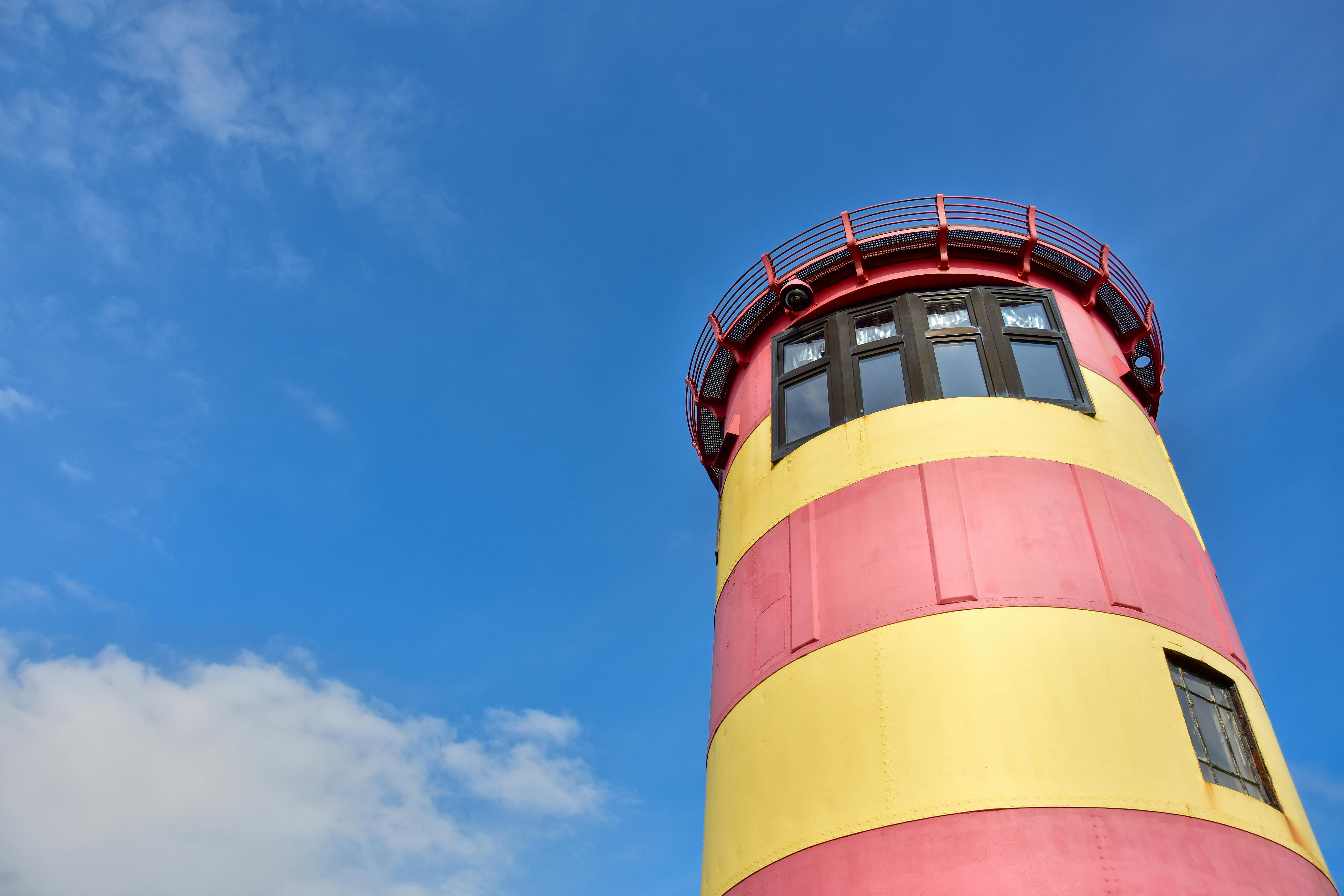 LowAngle Shot of a Red and Yellow Lighthouse · Free Stock Photo