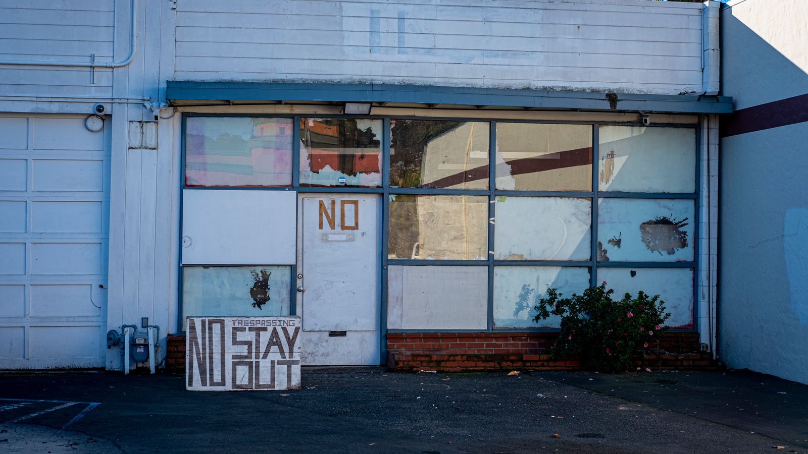Front view of an abandoned building with a prominent 'No Trespassing' sign, highlighting urban decay.