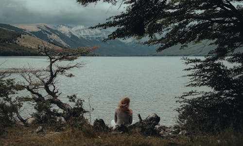 Back View of a Woman Sitting on the Lakeshore