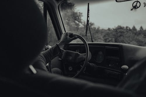 Grayscale Photo of a Person Driving a Car