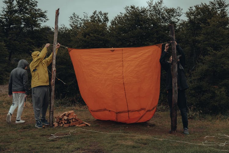 Campers Setting Up An Orange Tent