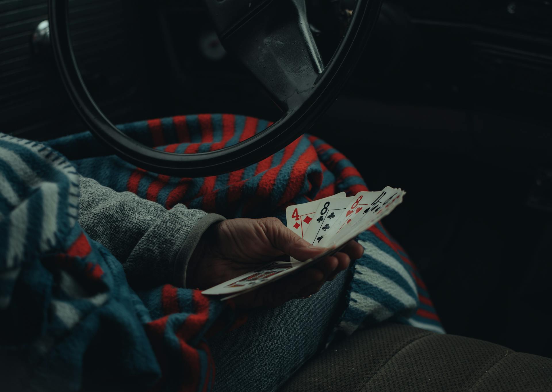 Close-up of a hand holding playing cards inside a vehicle, suggesting leisure travel.