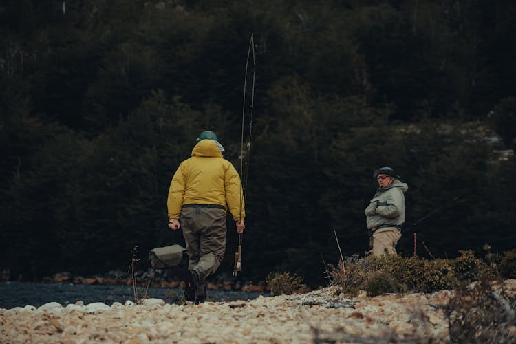 Man In Yellow Jacket Carrying A Fishing Rod