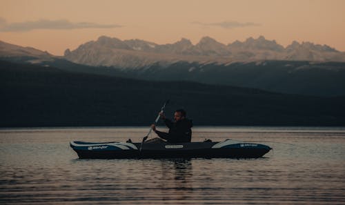 Man Riding a Blue Kayak on Lake