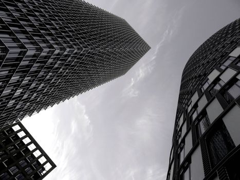 现代摩天大楼高耸于喜怒无常的多云天空下，这一景象引人注目，代表了城市建筑的特点