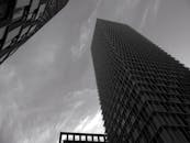 这张令人惊叹的黑白照片，捕捉了高耸的摩天大楼映衬在多云天空下的城市建筑景象