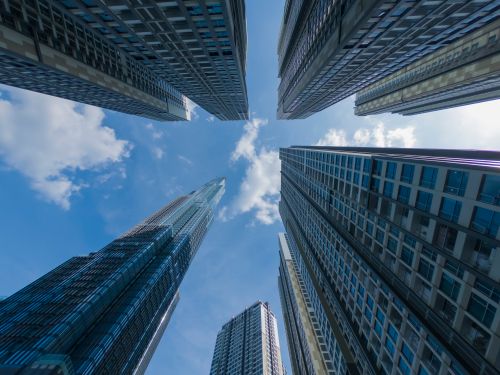 Free Looking up at modern skyscrapers against a bright blue sky with clouds. Stock Photo
